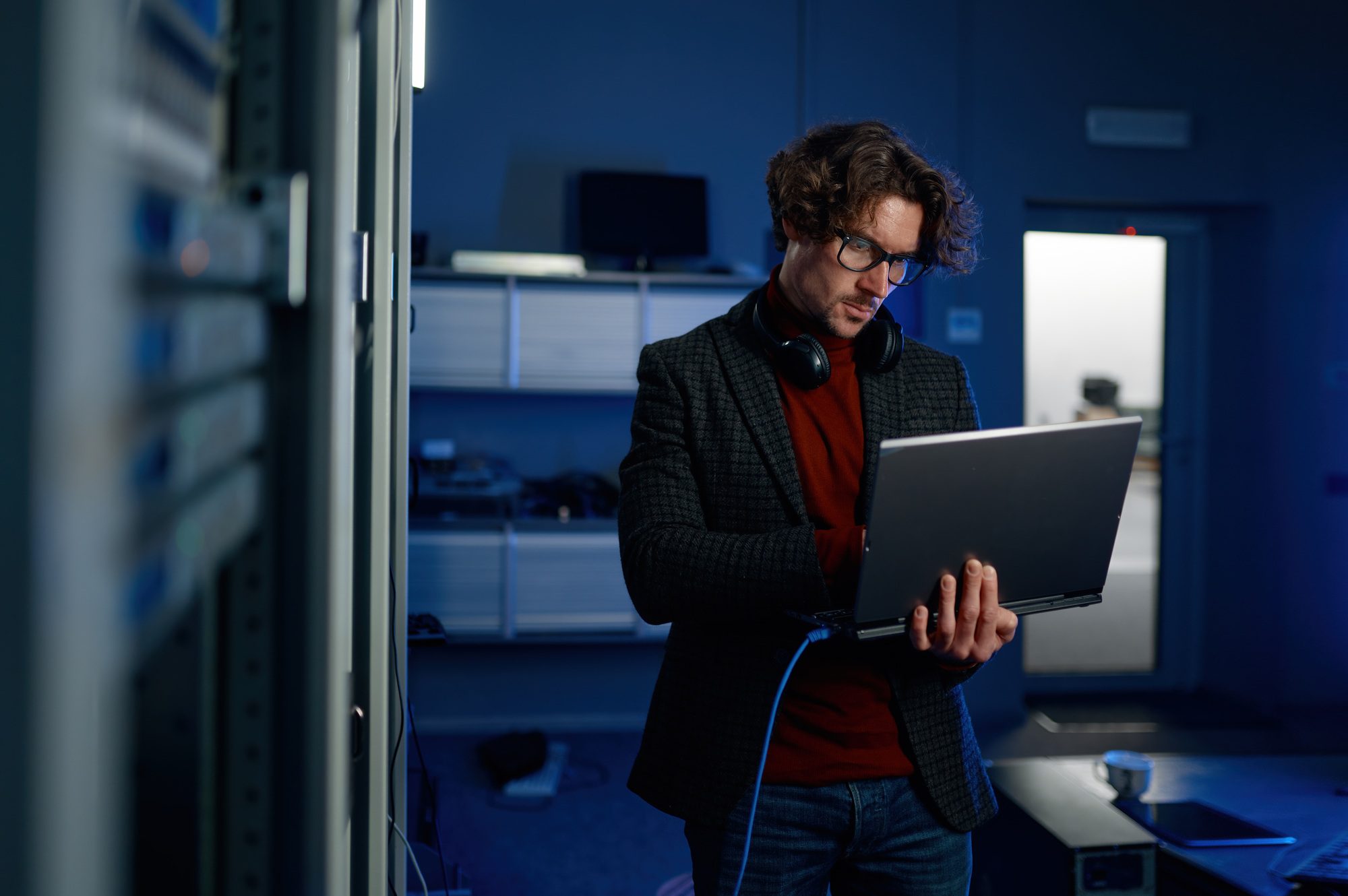 Data engineer holding laptop while working with supercomputer in server room