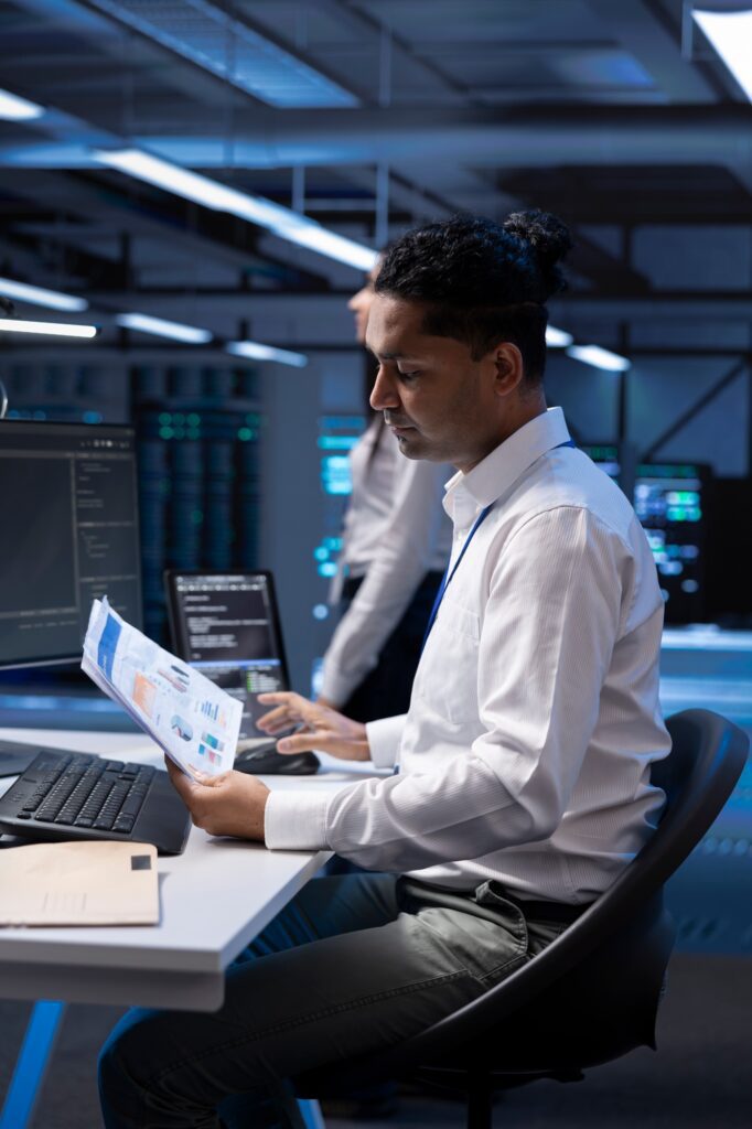 Serviceman in server hub checking documentation of supercomputers
