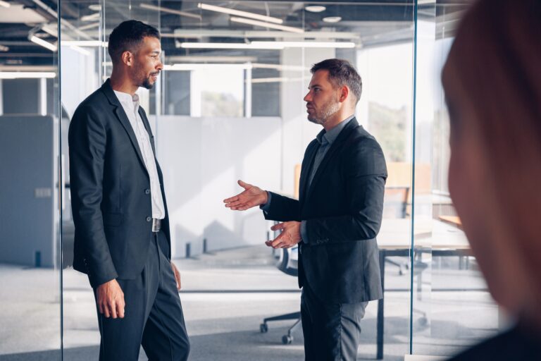 Two business colleagues talking together while standing in meeting room