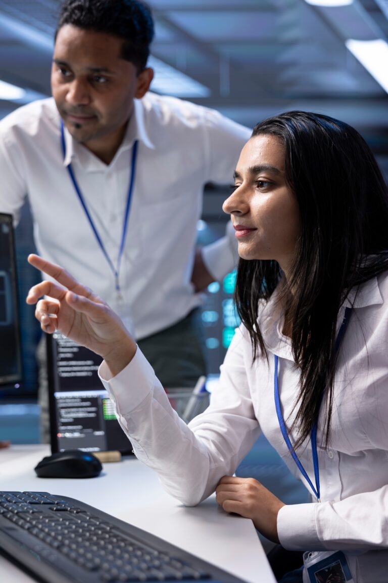 Coworkers in high tech data center checking equipment performance on computer