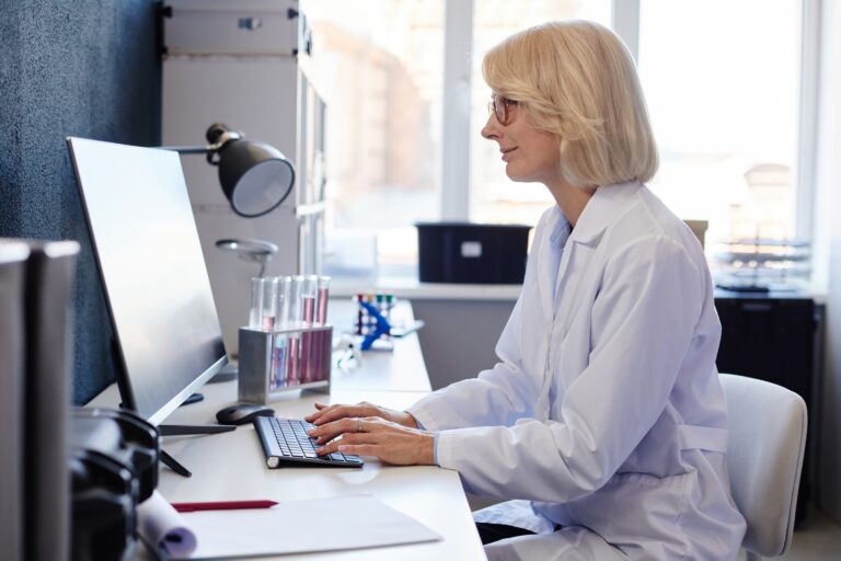 Female Lab Chemist Using Computer while Studying Chemicals in Pharmaceutical Laboratory