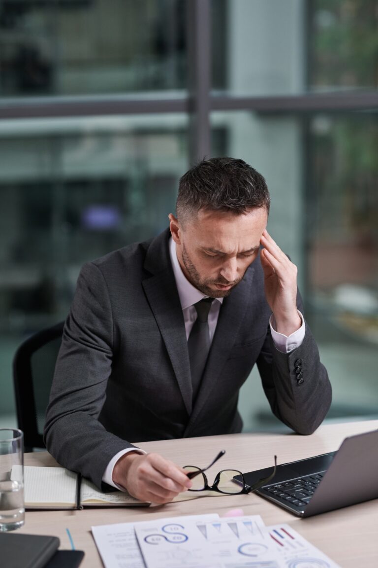 Overworked chief executive office with hand on temple feeling sick