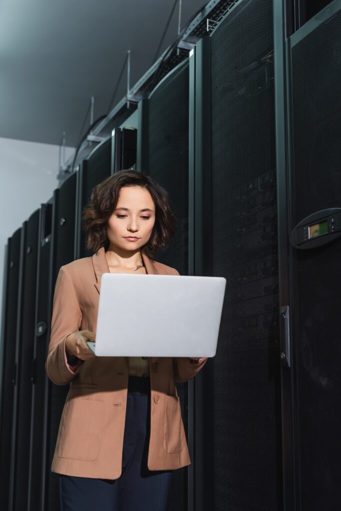 young programmer looking at laptop while working in data center