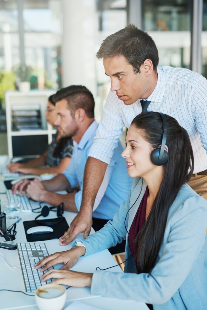 Shot of a young man assisting his colleague in a call center