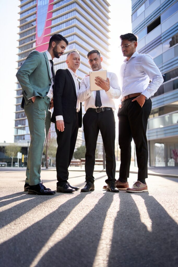 Vertical team diverse male professionals look concentrated at team leader tablet. Colleagues serious