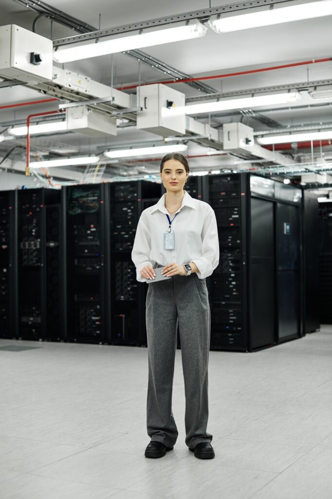 A woman in a white shirt works hard in a busy server room, keeping systems running smoothly.