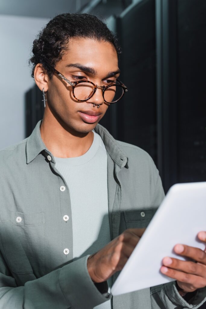 african american programmer looking at digital tablet during work in data center